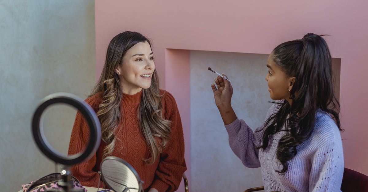 Should my friend with a drug offense as a minor apply for US visa waiver? - Young black woman applying makeup on face of friend