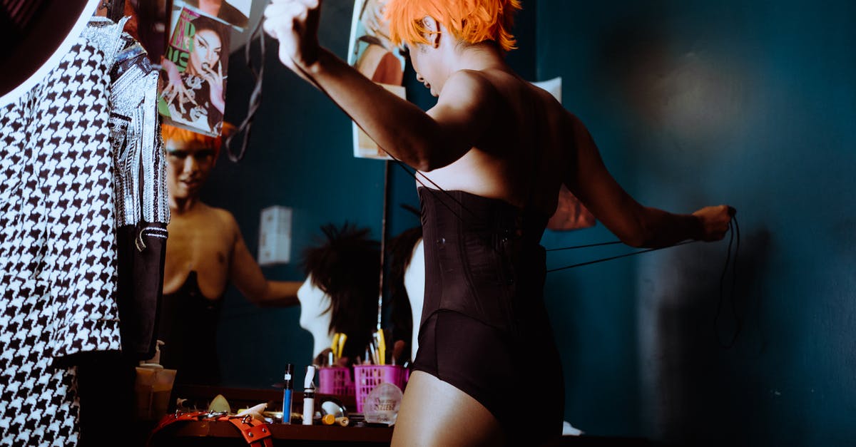 Showing evidence for informal savings - Sensual young ethnic transsexual guy tying corset in dressing room Showing evidence for informal savings - Sensual young ethnic transsexual guy tying corset in dressing room