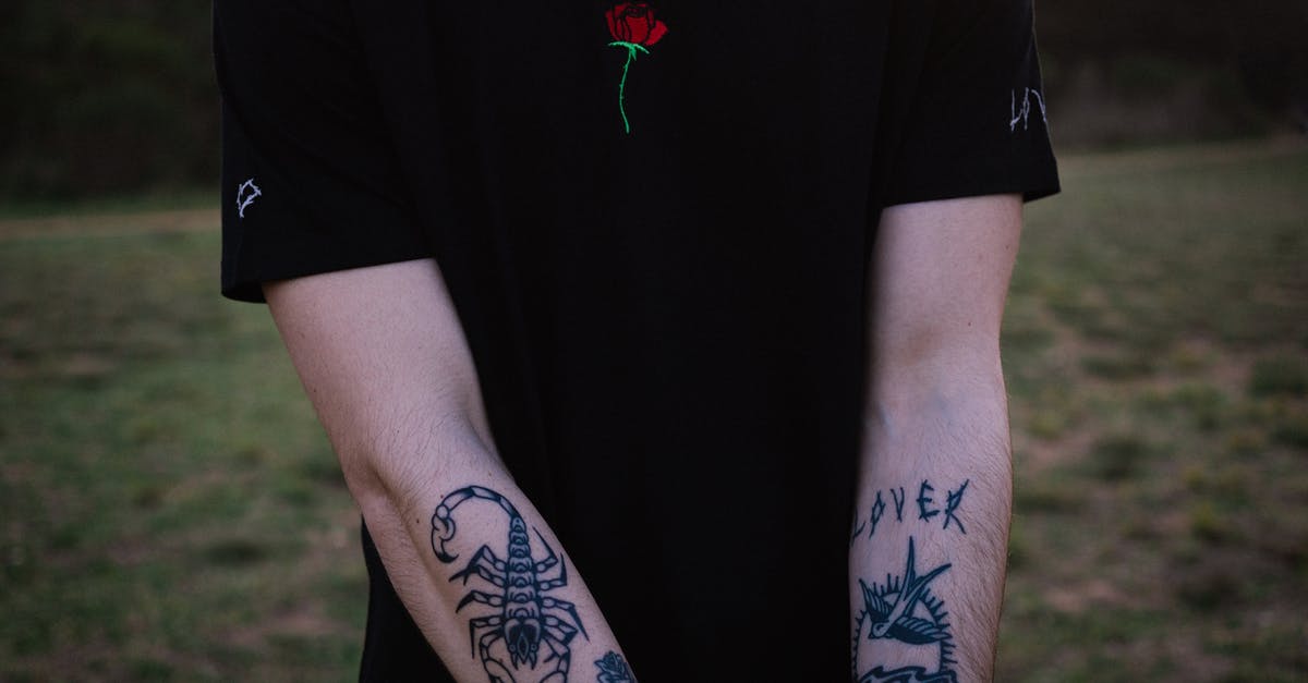 Showing evidence for informal savings - Crop tattooed man chilling in nature at sundown Showing evidence for informal savings - Crop tattooed man chilling in nature at sundown