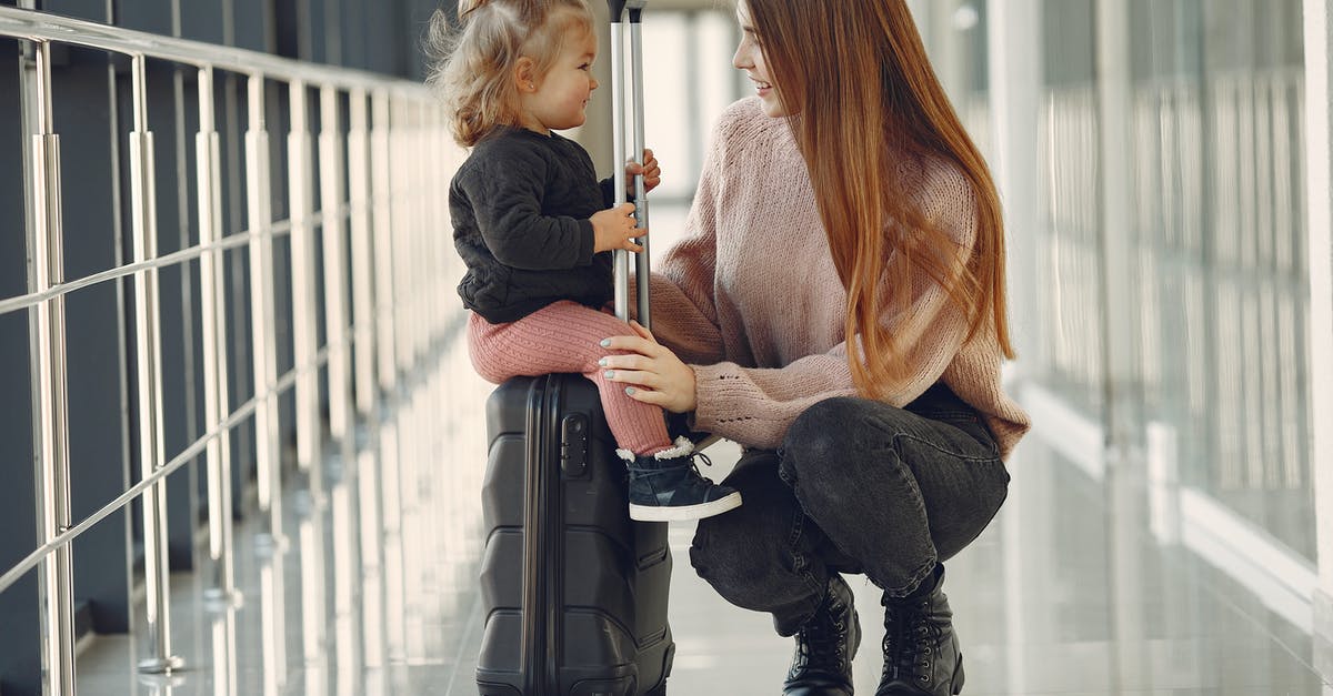 Sick child in airport - how can the airport help? [closed] - Full length of positive content woman and cute stylish blond little girl sitting on black suitcase in airport corridor while waiting for flight