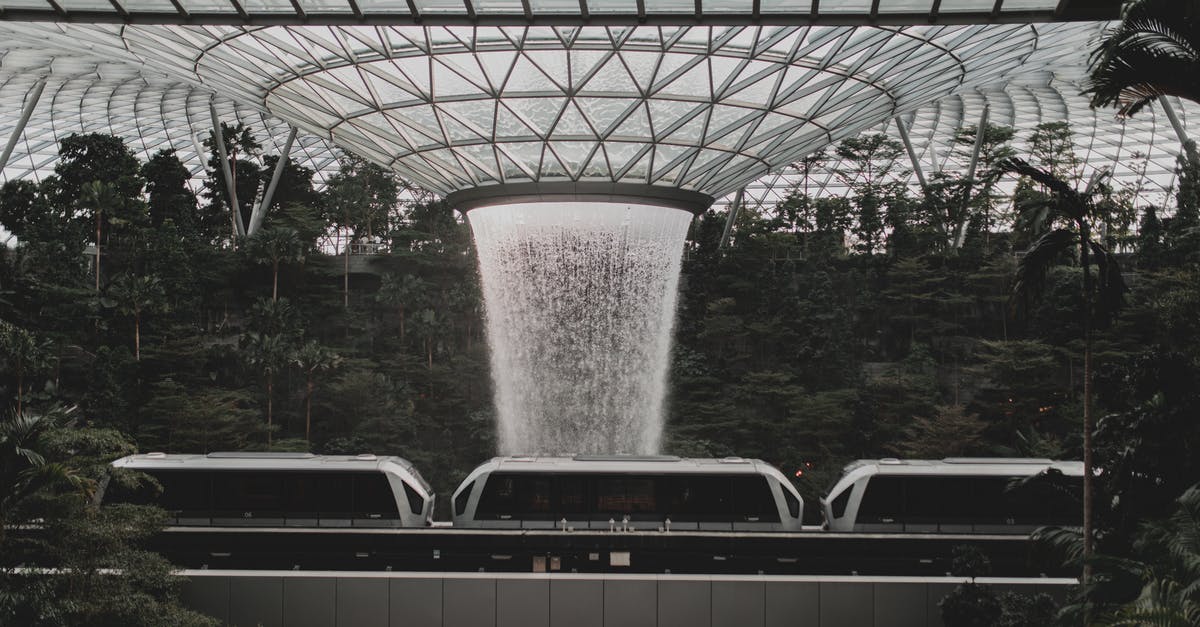 Singapore transit visa - Contemporary rail link train going under indoors waterfall streaming from creative glass ceiling in Jewel Changi Airport in Singapore Singapore transit visa - Contemporary rail link train going under indoors waterfall streaming from creative glass ceiling in Jewel Changi Airport in Singapore