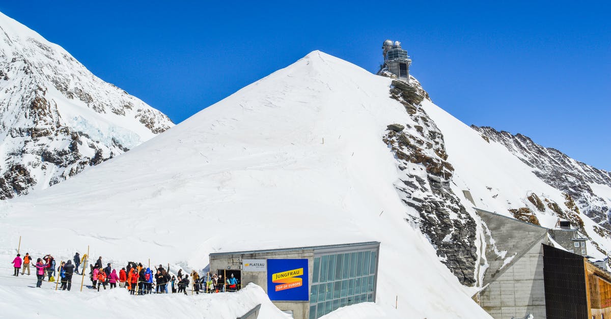 Ski rental for Mount Gassan - Anonymous group of tourists with skis near old building on snowy mountain under blue sky