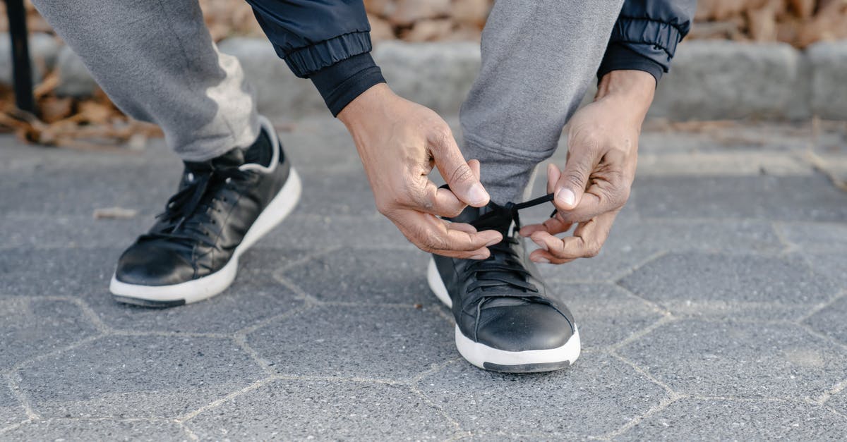 Skipping the final leg in a multi-stop flight, will there be any immigration problems? [duplicate] - Crop ethnic man tying shoelace on pavement