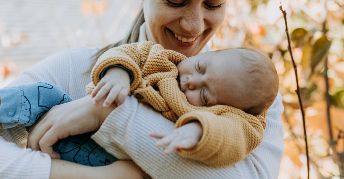 Sleeping aids for long flights [duplicate] - Smiling Woman Looking at her Sleeping Baby