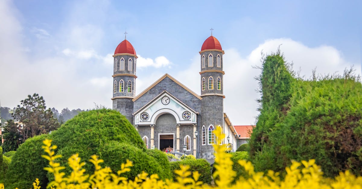 Sleeping near San Jose airport (Costa Rica) - Old Catholic church in well maintained garden against blue sky
