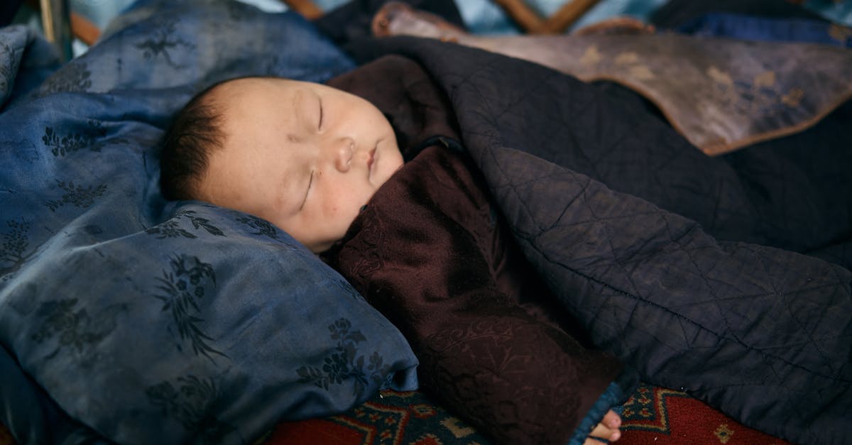 Sleeping overnight at Reagan National (DCA) airport - Side view of ethnic baby in warm national clothes sleeping under blanket on place covered by carpet Sleeping overnight at Reagan National (DCA) airport - Side view of ethnic baby in warm national clothes sleeping under blanket on place covered by carpet