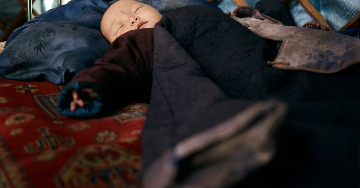Sleeping overnight at Reagan National (DCA) airport - Full length Asian infant lying on carpet while sleeping in warm national clothes under blanket Sleeping overnight at Reagan National (DCA) airport - Full length Asian infant lying on carpet while sleeping in warm national clothes under blanket
