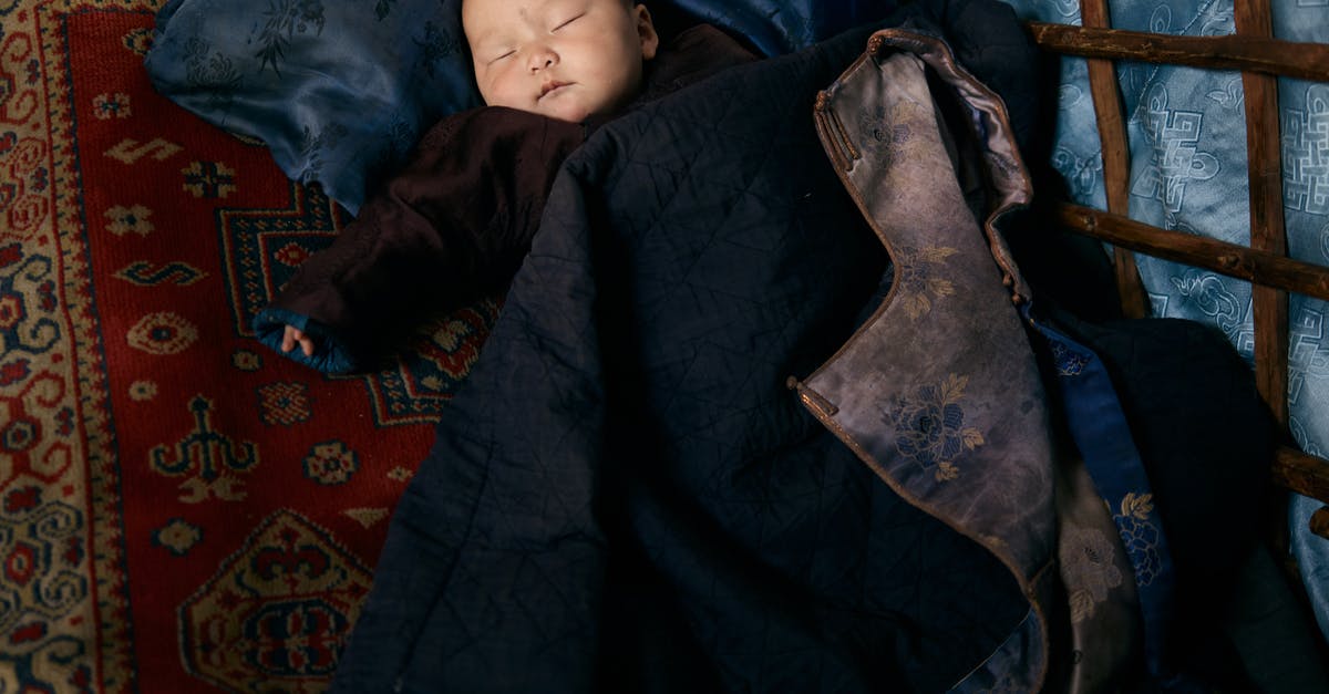 Sleeping overnight at Reagan National (DCA) airport - From above of full length sleeping Asian infant in warm clothes lying on carpet under adult man jacket with floral backing Sleeping overnight at Reagan National (DCA) airport - From above of full length sleeping Asian infant in warm clothes lying on carpet under adult man jacket with floral backing