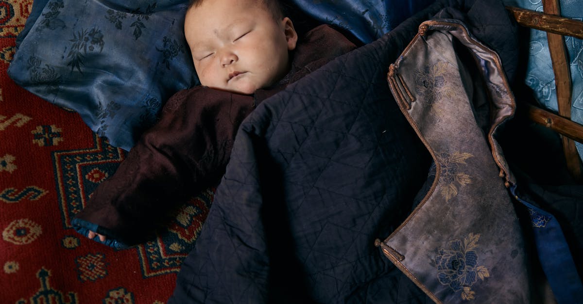 Sleeping overnight at Reagan National (DCA) airport - Top view of small ethnic baby in warm clothes sleeping on carpet and pillow under jacket with floral backing Sleeping overnight at Reagan National (DCA) airport - Top view of small ethnic baby in warm clothes sleeping on carpet and pillow under jacket with floral backing