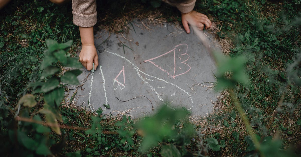 Small layover time. What to do? - High angle of unrecognizable child drawing with chalks on small piece of concrete block in grassy yard Small layover time. What to do? - High angle of unrecognizable child drawing with chalks on small piece of concrete block in grassy yard