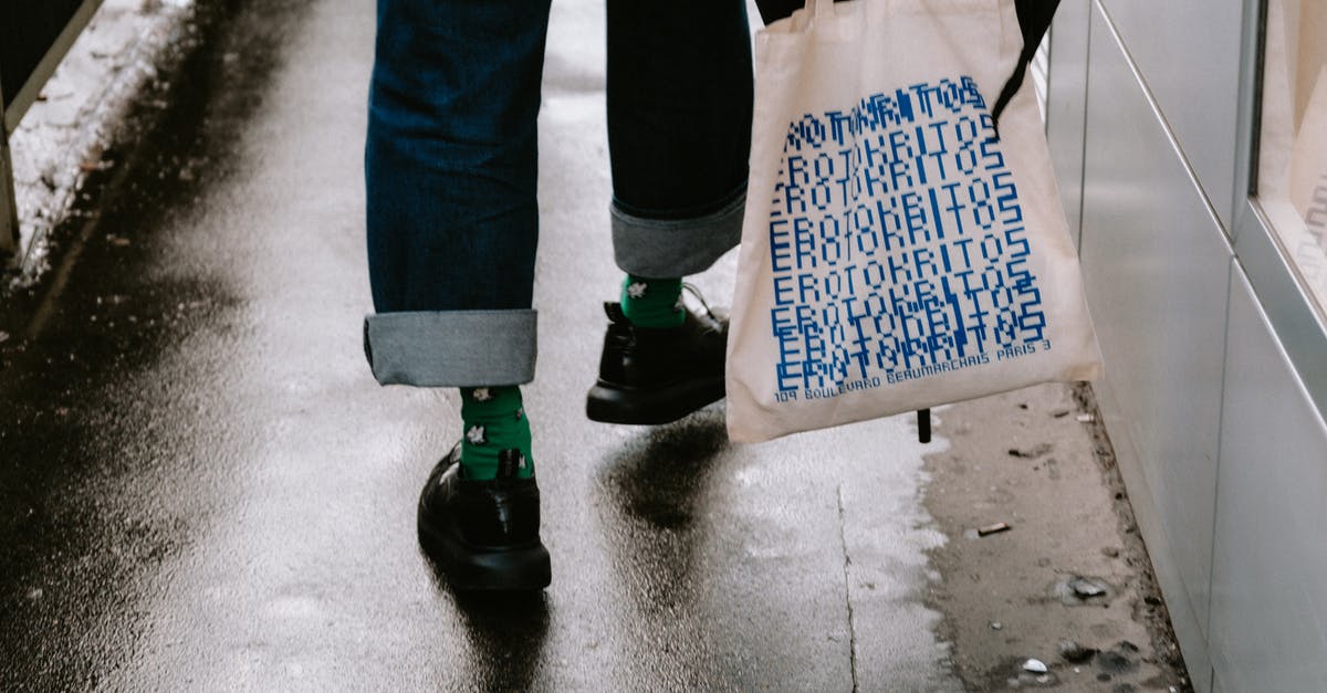 Small umbrella in the carry-on bag? - Person in Blue Denim Jeans and Black Shoes Holding Tote Bag and Black Umbrella Small umbrella in the carry-on bag? - Person in Blue Denim Jeans and Black Shoes Holding Tote Bag and Black Umbrella