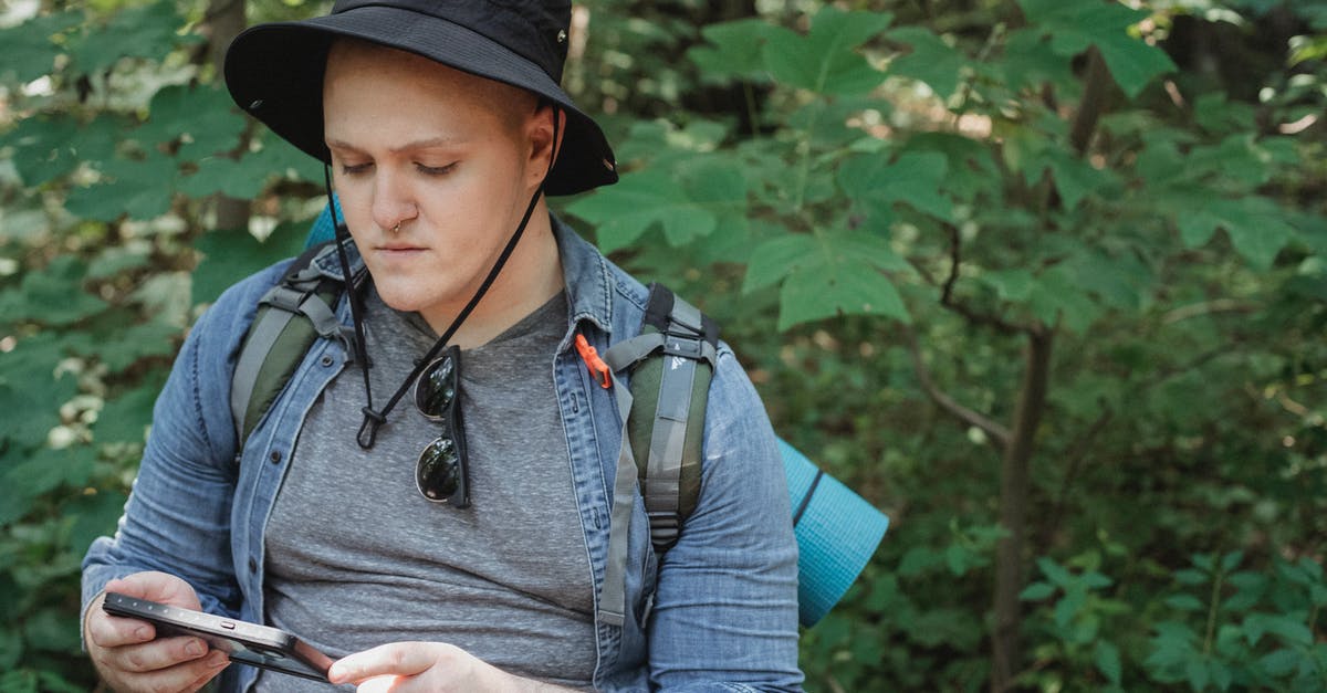 Social Travel App for managing Itinerary - Serious young man using tablet in forest during hiking tour Social Travel App for managing Itinerary - Serious young man using tablet in forest during hiking tour