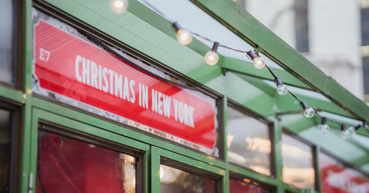 Solo-Driving from Florida to New York During the Winter - Low angle red signboard with Christmas In New York inscription hanging on glass showcase of shop on city street Solo-Driving from Florida to New York During the Winter - Low angle red signboard with Christmas In New York inscription hanging on glass showcase of shop on city street