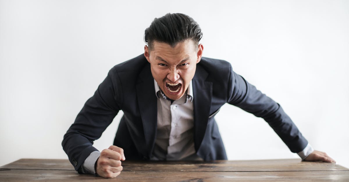 Spelling error in Malaysian eVisa - Expressive angry businessman in formal suit looking at camera and screaming with madness while hitting desk with fist Spelling error in Malaysian eVisa - Expressive angry businessman in formal suit looking at camera and screaming with madness while hitting desk with fist