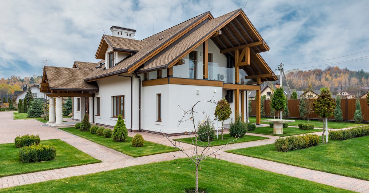 Stamping of non-EU passports with residence permit - Exterior of modern cottage house with columns and balcony surrounded by green grass and trees Stamping of non-EU passports with residence permit - Exterior of modern cottage house with columns and balcony surrounded by green grass and trees
