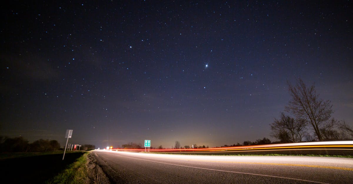 Star Alliance - direct routes - From below of glowing asphalt road with fence near trees and road signs under picturesque night sky with luminous stars at sundown Star Alliance - direct routes - From below of glowing asphalt road with fence near trees and road signs under picturesque night sky with luminous stars at sundown