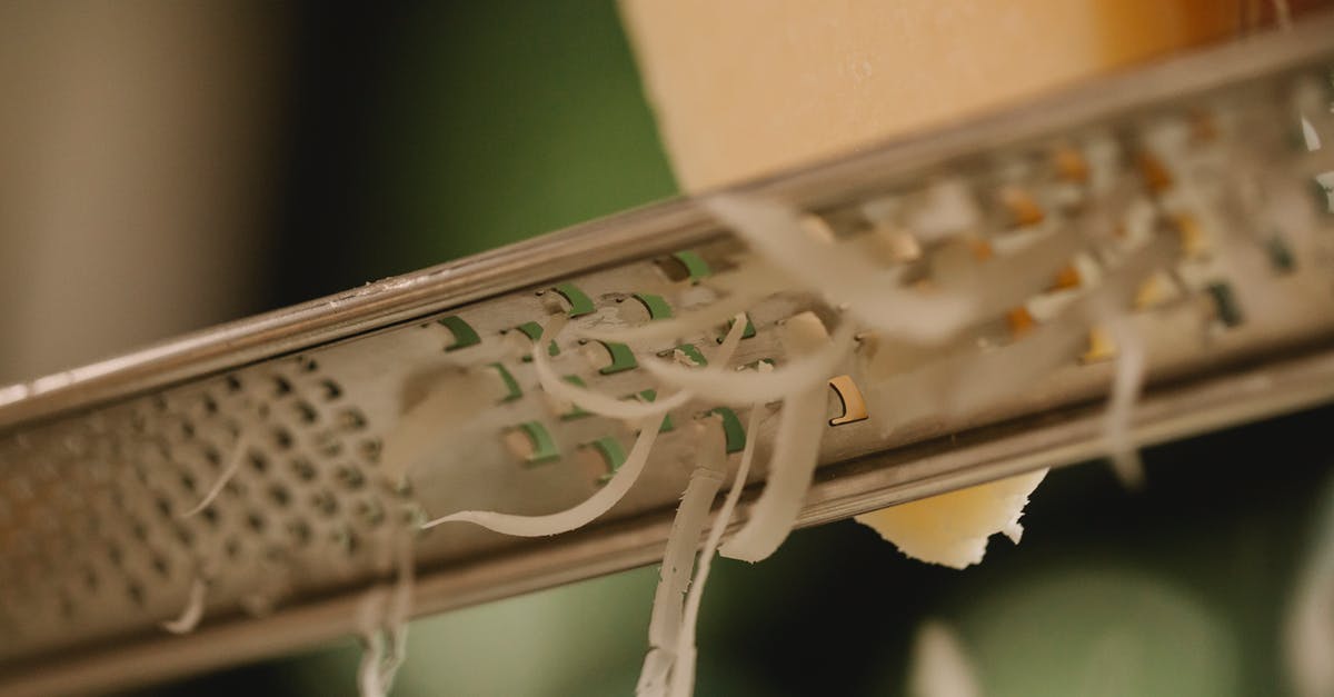 Suitcases: hard or soft? Canvas, polycarbonate or something else? - Closeup of tasty hard cheese grating on narrow stainless grater against blurred kitchen background Suitcases: hard or soft? Canvas, polycarbonate or something else? - Closeup of tasty hard cheese grating on narrow stainless grater against blurred kitchen background