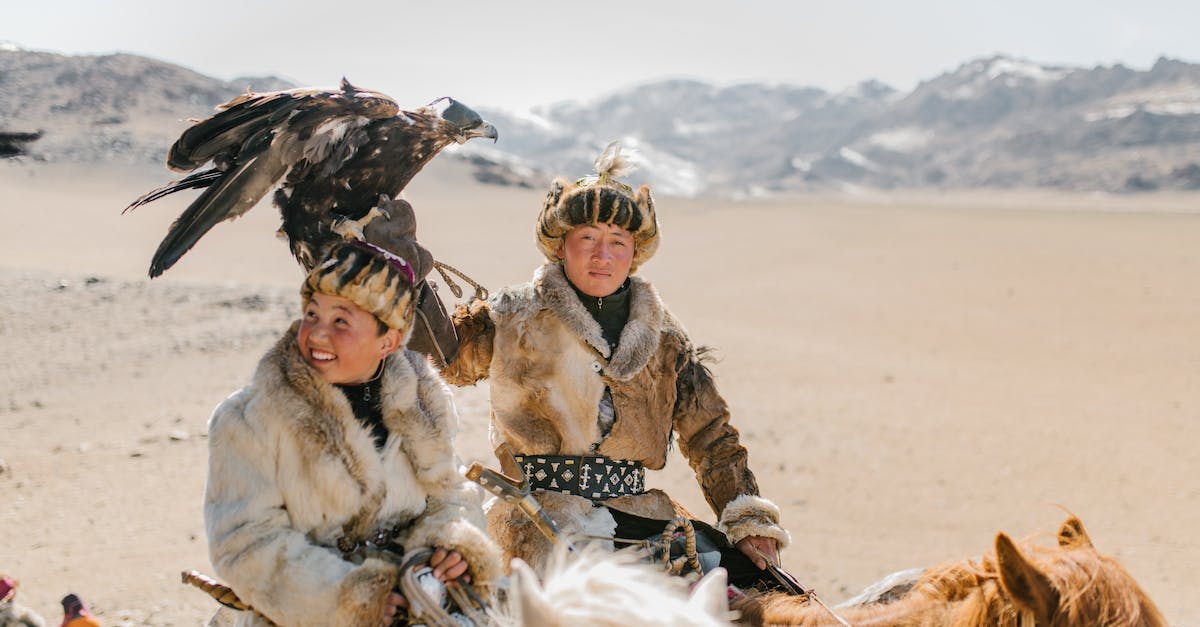 Sustainable hunting in South-East Asia - Positive Mongolian eagle hunters riding horses on mountainous terrain Sustainable hunting in South-East Asia - Positive Mongolian eagle hunters riding horses on mountainous terrain