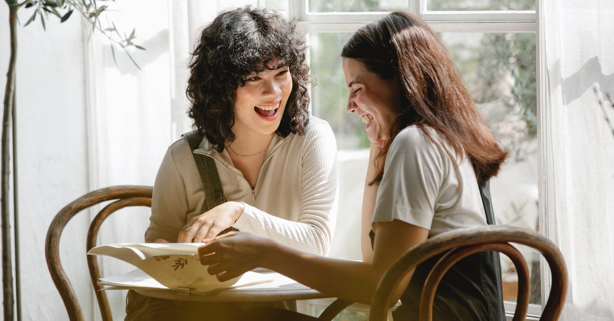 Swap places in business class with friend [duplicate] - Laughing multiracial female colleagues wearing uniform flipping pages of papers while discussing work together