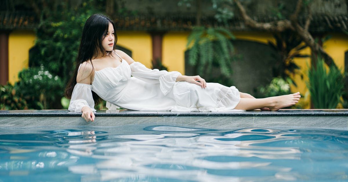 Swimming pool dressing code in Luxembourg - Attractive Asian woman lying on edge of pool
