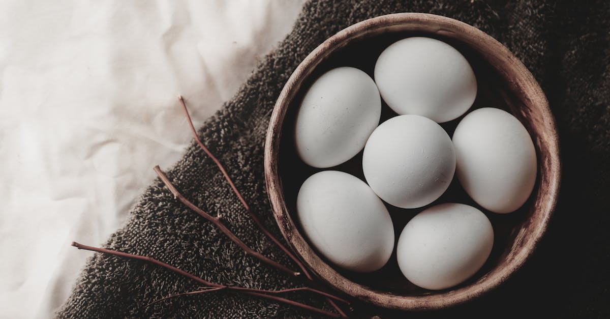 Taking dried food into another country through customs - Top view of chicken eggs in wicker bowl placed near twigs on gray towel