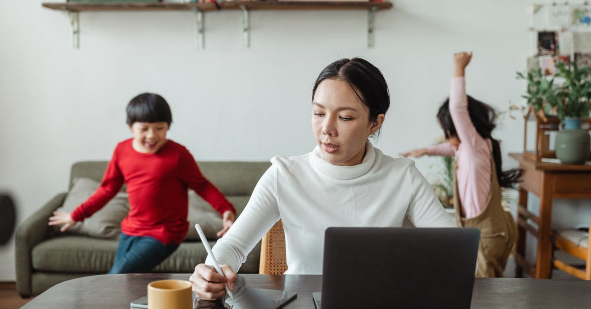 Taking my husband and son on tourist visa while I am going on business visa - Asian mother working online using laptop and taking notes on tablet with stylus and cheerful children making noise and running behind in living room Taking my husband and son on tourist visa while I am going on business visa - Asian mother working online using laptop and taking notes on tablet with stylus and cheerful children making noise and running behind in living room