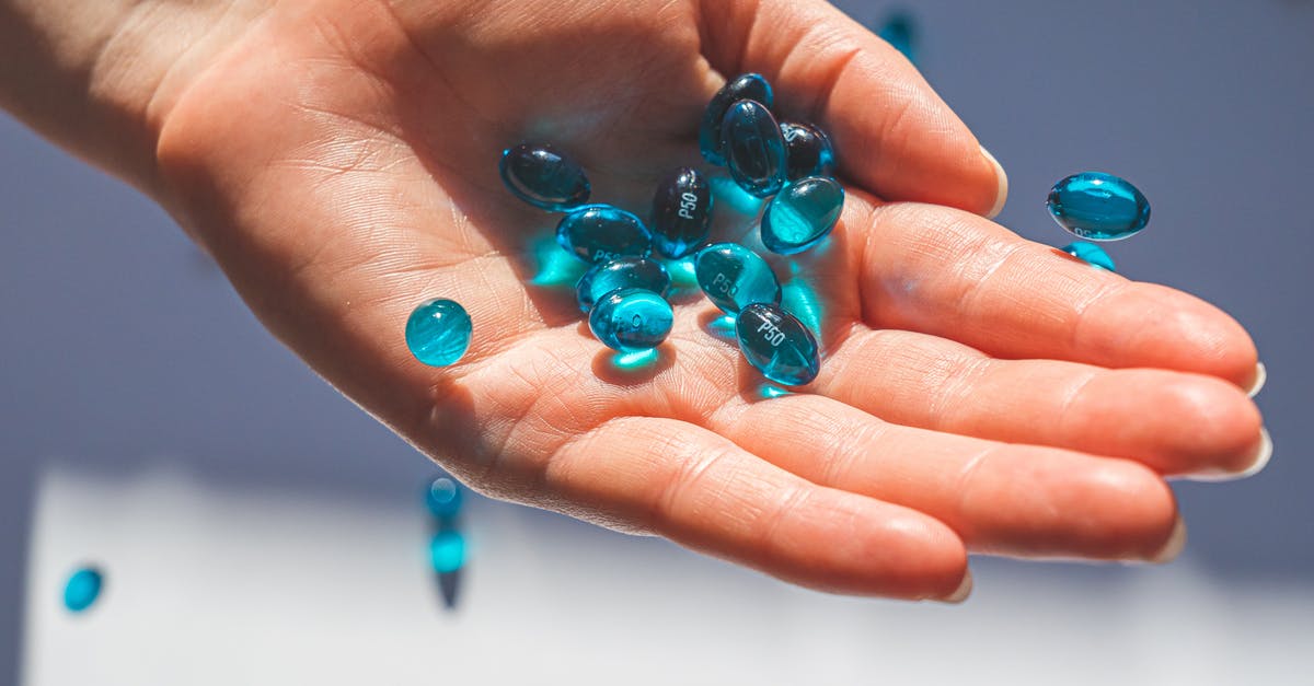 Taking personal prescription drugs to London? - Person Holding Blue Pills Taking personal prescription drugs to London? - Person Holding Blue Pills