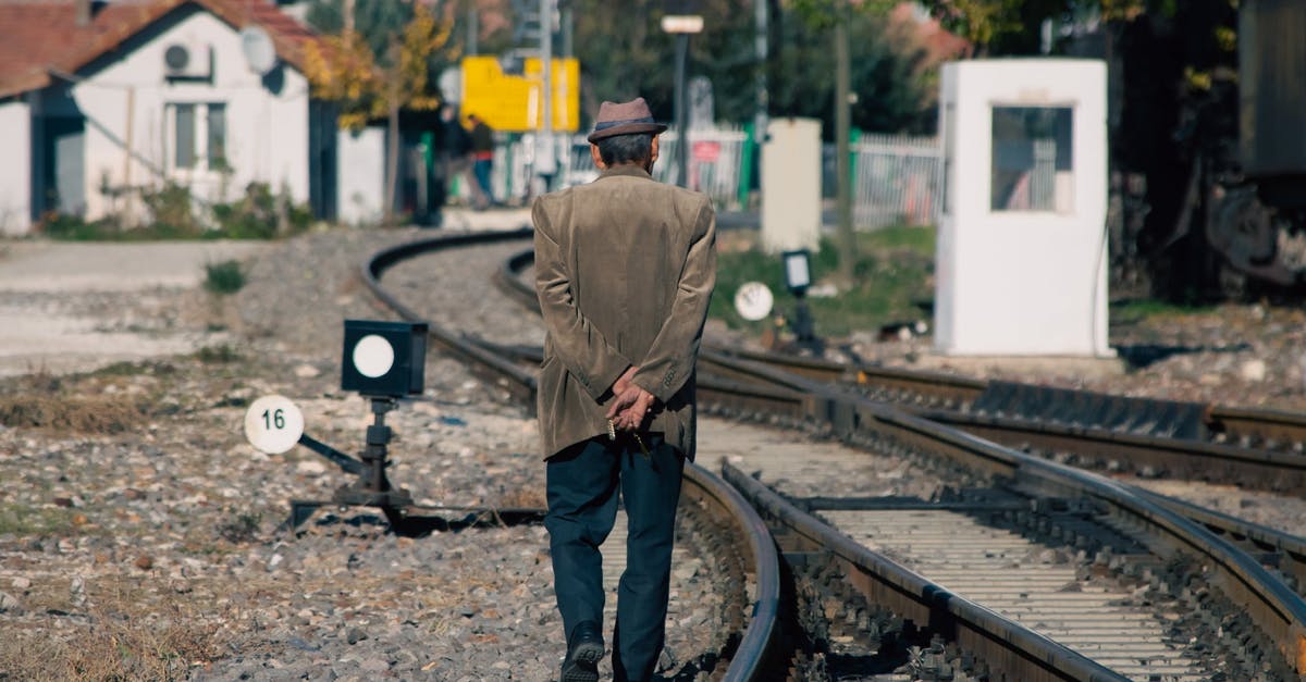 The Haramain Railway or Mecca-Medina Railway - Man in Brown Jacket and Black Pants Standing on Train Rail The Haramain Railway or Mecca-Medina Railway - Man in Brown Jacket and Black Pants Standing on Train Rail