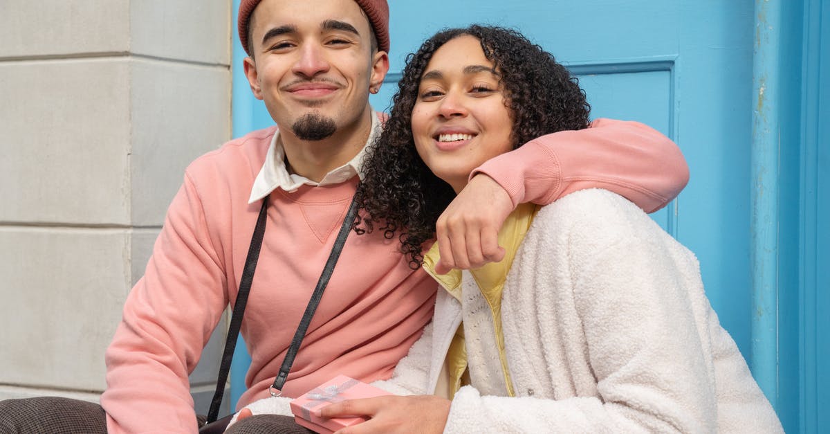 Time taken to receive ESTA approval - Smiling Hispanic boyfriend hugging girlfriend with gift box while sitting on street near building and looking at camera during date Time taken to receive ESTA approval - Smiling Hispanic boyfriend hugging girlfriend with gift box while sitting on street near building and looking at camera during date
