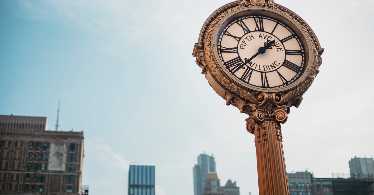 Time to get to KUL from center of Kuala Lumpur - From below of aged metal clock tower located in city center with high towers Time to get to KUL from center of Kuala Lumpur - From below of aged metal clock tower located in city center with high towers