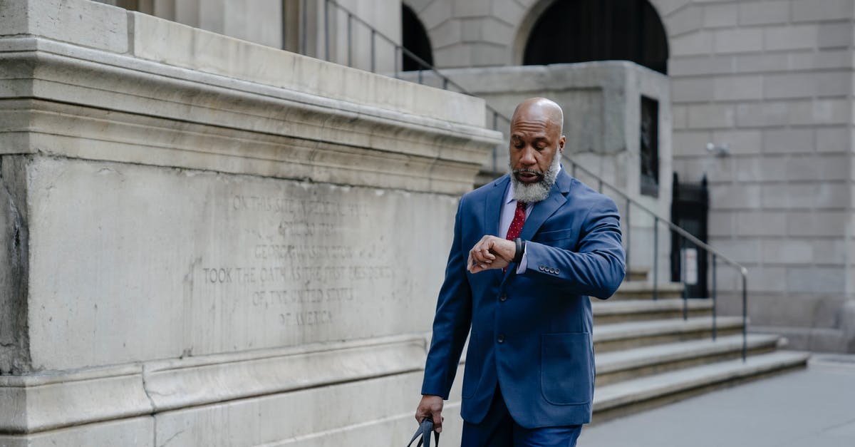 Time to Recheck Bag? - An Elderly Man Looking at his Wristwatch while Walking on the Street Time to Recheck Bag? - An Elderly Man Looking at his Wristwatch while Walking on the Street