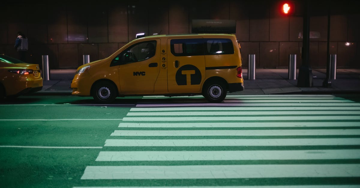 Tipping in shared ride vans - Comfortable yellow minivan cab parked on city asphalt road near traffic light at night Tipping in shared ride vans - Comfortable yellow minivan cab parked on city asphalt road near traffic light at night