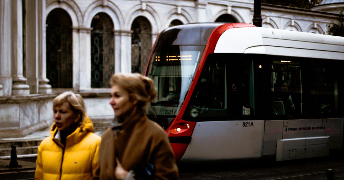 Tips for London Public Transport for a first visit with a 3 year old [closed] - Middle aged female travelers in warm outwears walking together on street near modern tramway train and aged historical buildings