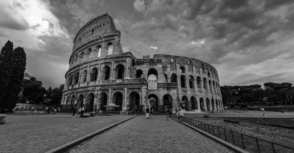 Tourist visa for Spain with adverse UK Immigration history - Black and white of historic Colosseum with tourists walking on paved square in Madrid Tourist visa for Spain with adverse UK Immigration history - Black and white of historic Colosseum with tourists walking on paved square in Madrid
