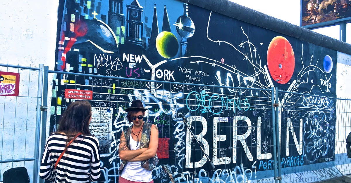 Train from Krakow to Berlin - Man Wearing Black Waistcoat and White Tank Tops Standing Near a Mural Train from Krakow to Berlin - Man Wearing Black Waistcoat and White Tank Tops Standing Near a Mural