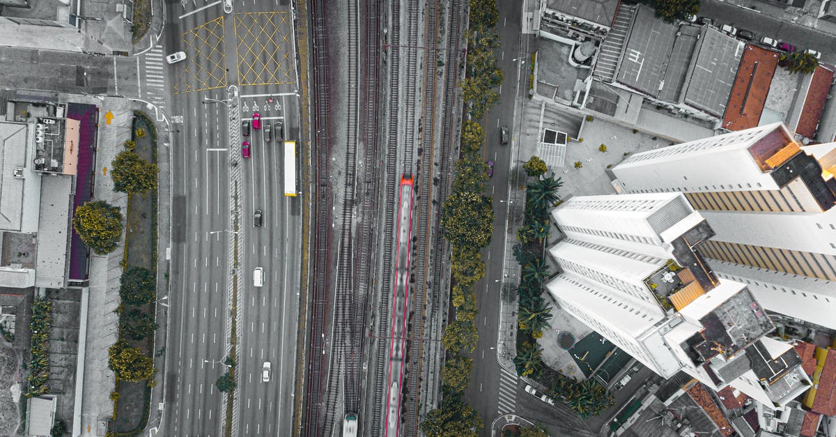 Train Route from CDG to Calais - Top view of asphalt roadways and railroads with driving vehicles near high house facades in town Train Route from CDG to Calais - Top view of asphalt roadways and railroads with driving vehicles near high house facades in town