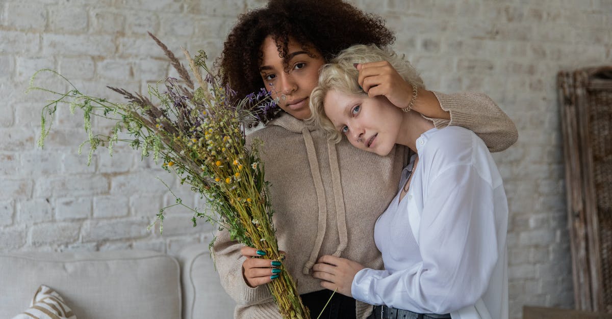 Transfer time at Newark domestic to domestic different carriers - Multiracial women hugging in cozy room Transfer time at Newark domestic to domestic different carriers - Multiracial women hugging in cozy room