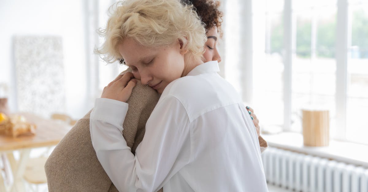 Transfer time at Newark domestic to domestic different carriers - Multiracial women tenderly hugging in room Transfer time at Newark domestic to domestic different carriers - Multiracial women tenderly hugging in room