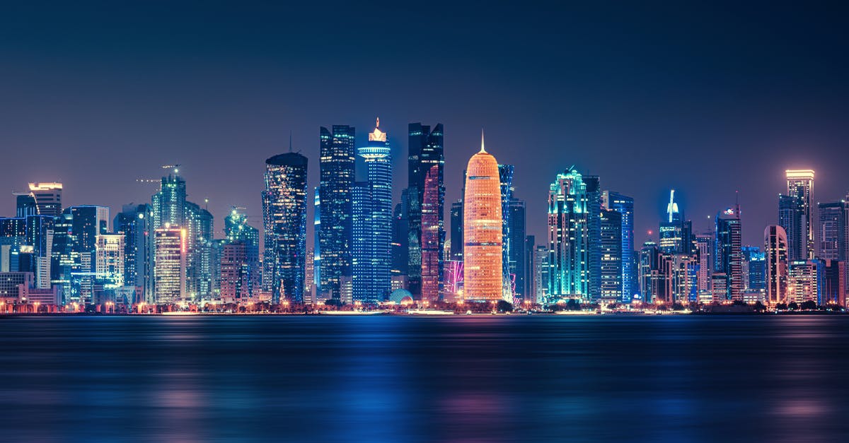 Transit Visa in Doha - Body of Water Across City Buildings during Nighttime Transit Visa in Doha - Body of Water Across City Buildings during Nighttime
