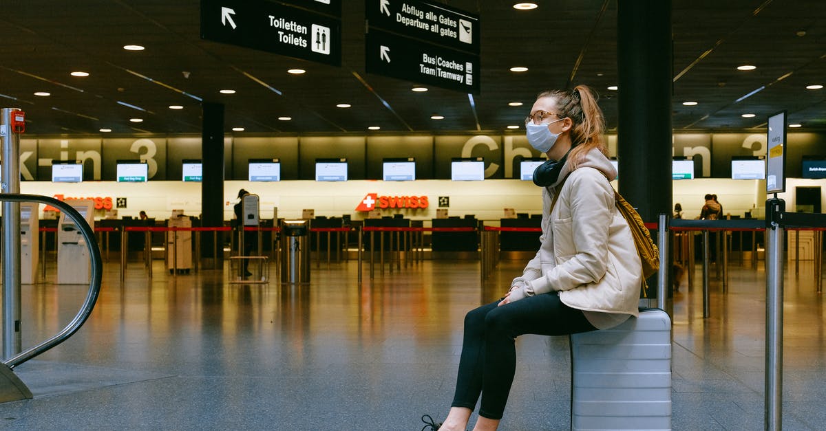 Transiting Budapest Airport in Times of COVID - Woman Sitting on Luggage Transiting Budapest Airport in Times of COVID - Woman Sitting on Luggage