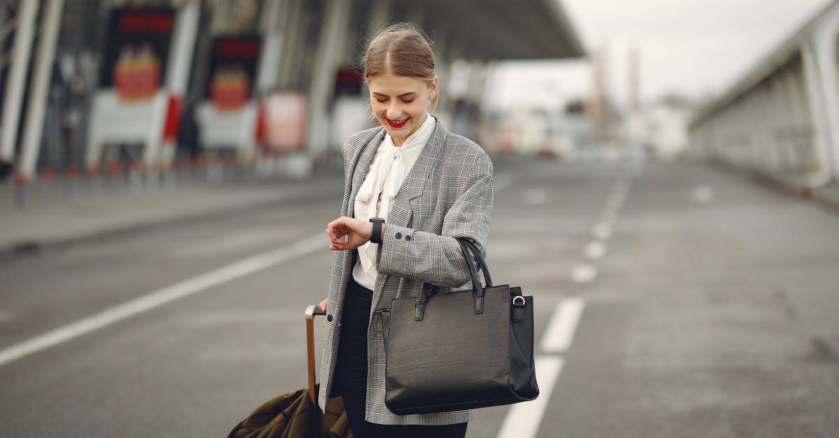 Transiting Budapest Airport in Times of COVID - Positive young businesswoman with suitcase hurrying on flight on urban background Transiting Budapest Airport in Times of COVID - Positive young businesswoman with suitcase hurrying on flight on urban background