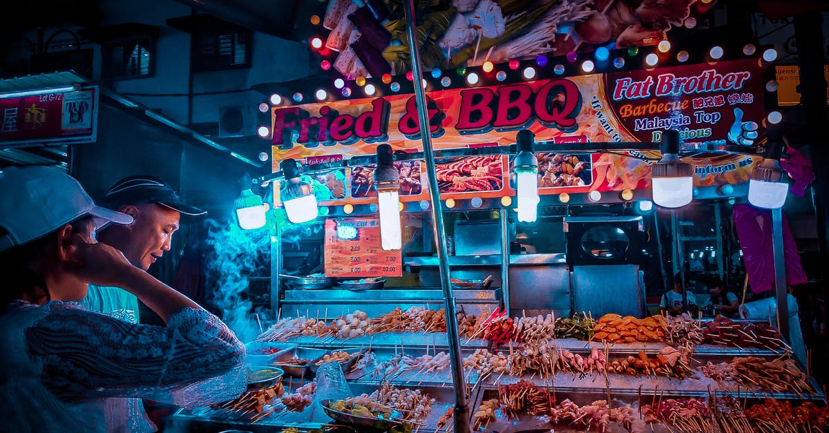 Transiting through Kuala Lumpur - two different carriers - Customer choosing raw kebab in street stall at night Transiting through Kuala Lumpur - two different carriers - Customer choosing raw kebab in street stall at night