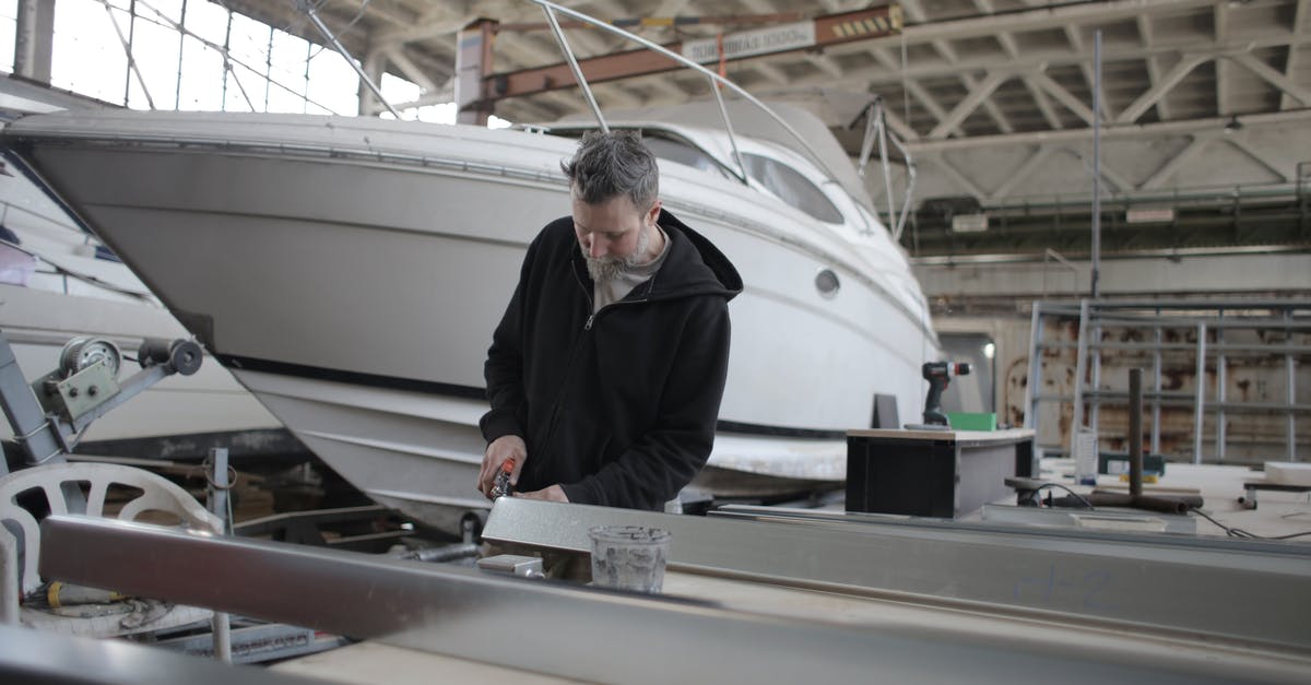 Transport bread maker on Turkish Airlines - Concentrated bearded adult workman in casual wear working with metal detail near boat in garage