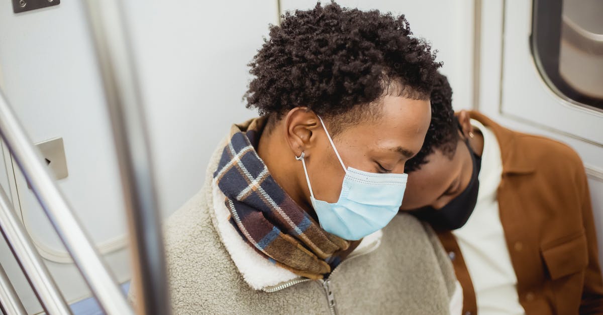 Transport from Canary Islands to Casablanca? [closed] - From above of African American homosexual couple wearing casual clothes in protective masks sleeping while riding in subway train together