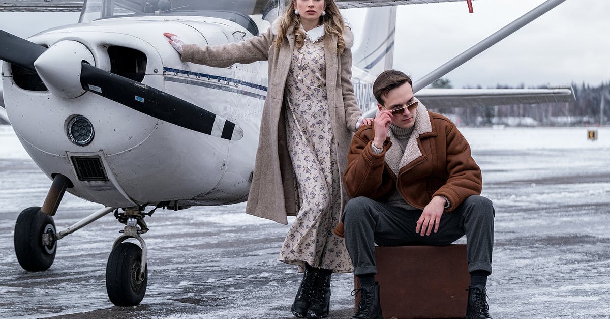 Transport from Frankfurt Hahn Airport [closed] - Stylish couple in outerwear standing near propeller aircraft in airport