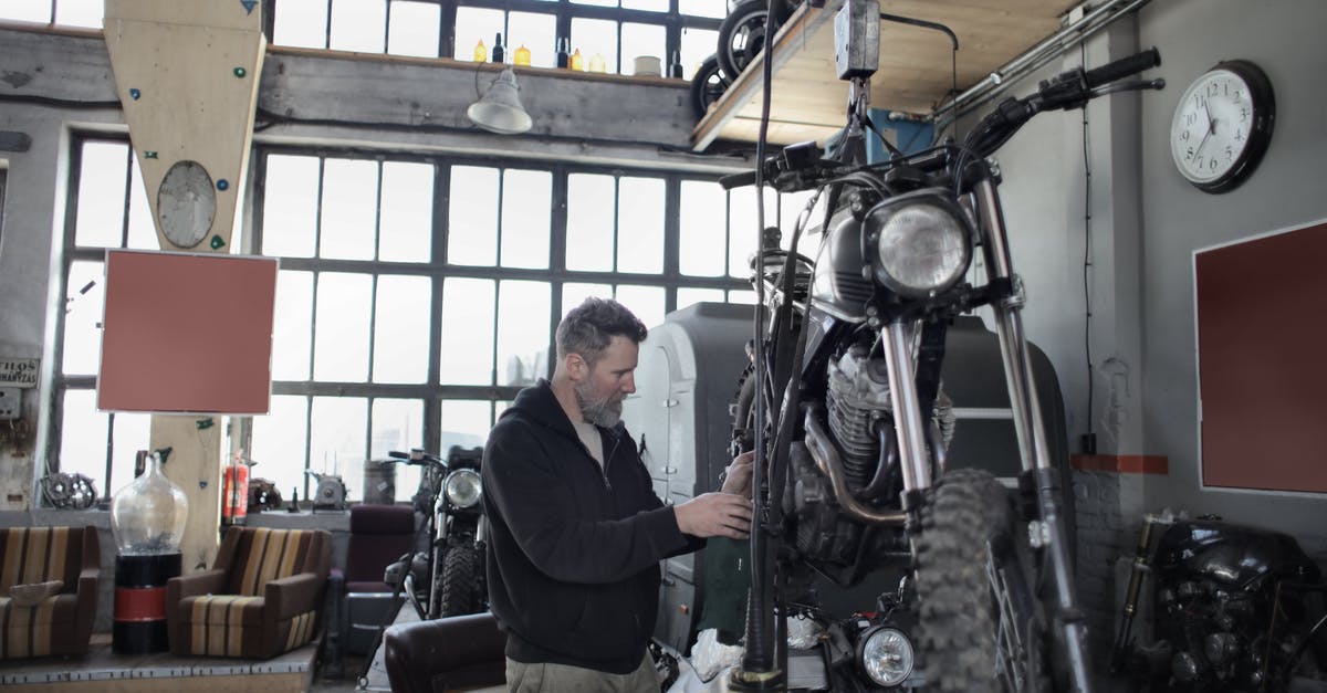 Transport kitchen stand mixer from China to Europe by plane - Side view of bearded adult mechanic in casual uniform standing near motorcycle and working with engine in workshop Transport kitchen stand mixer from China to Europe by plane - Side view of bearded adult mechanic in casual uniform standing near motorcycle and working with engine in workshop