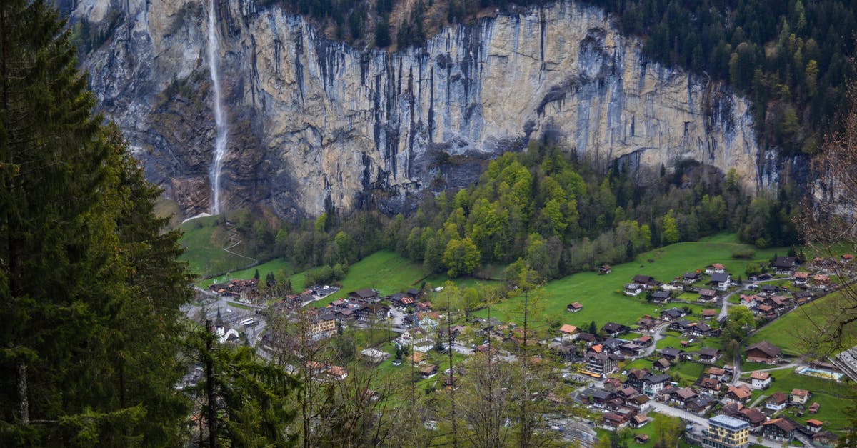 Travel from Germany to Switzerland on an Australian Refugee Travel Document - From above of picturesque rocky mountain covered with coniferous trees with waterfall flowing above small village of Lauterbrunnen in Switzerland Travel from Germany to Switzerland on an Australian Refugee Travel Document - From above of picturesque rocky mountain covered with coniferous trees with waterfall flowing above small village of Lauterbrunnen in Switzerland