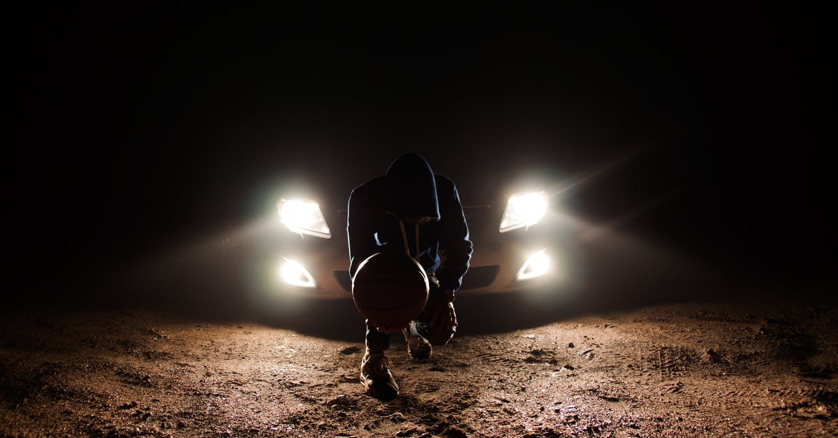 Travel from the UAE to Lithuania by car - Man Against the Vehicle Headlight Squatting Holding Ball