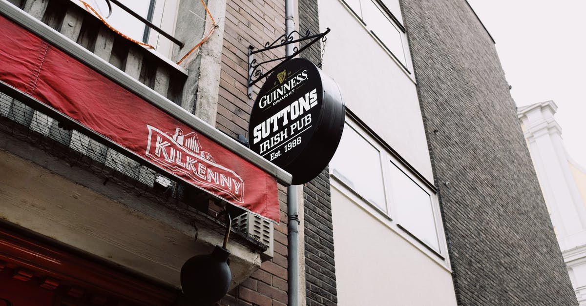 Travel to UK on a business visa from old company - Signboard of beer pub near modern brick building in tourist city Travel to UK on a business visa from old company - Signboard of beer pub near modern brick building in tourist city