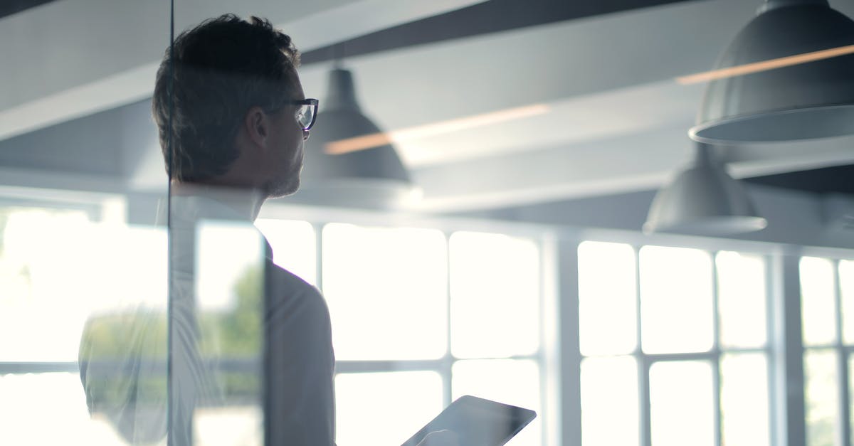Travel to UK on a business visa from old company - Formal man with tablet giving presentation in office Travel to UK on a business visa from old company - Formal man with tablet giving presentation in office